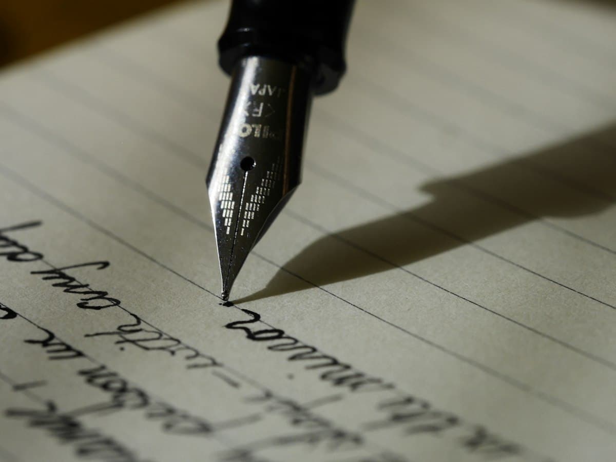 A fountain pen resting on a handwritten page, shadow falling across the lines